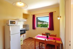 a small kitchen with a table and a refrigerator at Apartments Corfu Sun Pool Side in Benitses