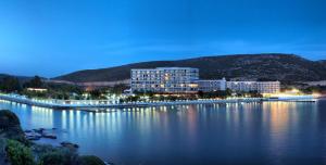 un grand bâtiment sur la rive d'un lac la nuit dans l'établissement Tusan Beach Resort - All Inclusive, à Kusadası