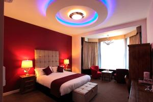 a bedroom with a large bed and a red wall at The Pearl Hotel in Peterborough