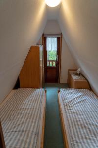 Cette chambre mansardée comprend 2 lits et une fenêtre. dans l'établissement Naturcamping Perlin Ferienhaus, à Perlin