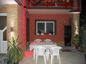 une table et des chaises sur une terrasse avec un mur rouge dans l'établissement Apartments Joce, à Ohrid