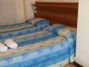 una camera con tre letti blu con asciugamani di Hotel Lombardia a Seveso