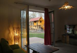 una sala de estar con una puerta corredera de cristal que da a una casa en Ferienwohnungen Zum Baumhaus en Burg (Spreewald)