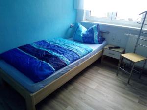 a bed in a room with a blue wall at Pension zum Ringelberg in Erfurt