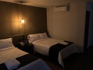 una camera d'albergo con due letti e una luce di Hotel Isabel a Puebla