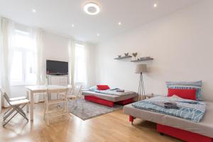 a living room with a bed and a dining room at Bright Red Heart Apartment in Leopoldstadt in Vienna