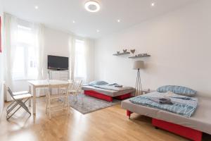 a room with two beds and a table and a dining room at Bright Red Heart Apartment in Leopoldstadt in Vienna