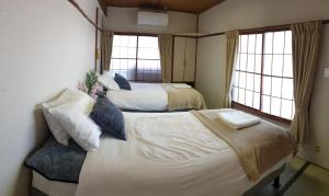 2 Betten in einem Zimmer mit 2 Fenstern in der Unterkunft Myoko Ski Lodge in Akakura Village in Myōkō