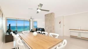 a living room with a table and chairs and the ocean at Amira Penthouse Main Beach in Gold Coast