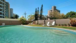 a large swimming pool with two white chairs next to a building at Amira Penthouse Main Beach in Gold Coast