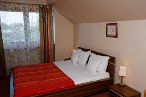 a bedroom with a bed with white sheets and a window at Pension Stejeris in Braşov