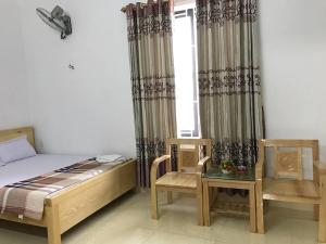 a bedroom with a bed and two chairs and a window at Nhà nghỉ Mạnh Bình in Hai Phong