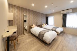 two beds in a hotel room with a desk and a desk at SARASA HOTEL Dotonbori in Osaka