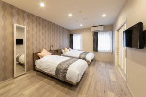 two beds in a room with a flat screen tv at SARASA HOTEL Dotonbori in Osaka
