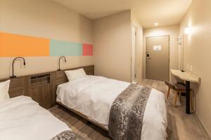 a hotel room with two beds and a desk at SARASA HOTEL Dotonbori in Osaka