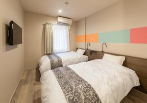 a hotel room with two beds and a television at SARASA HOTEL Dotonbori in Osaka