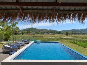 a swimming pool with a blue umbrella on top of it at Cloud9 Holiday Cottages in Pantai Cenang