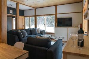 a living room with a blue couch and a tv at Nozawa Gondola Apartments in Nozawa Onsen