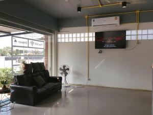 a living room with a black couch and a tv at Best Bed Suvarnabhumi Hostel in Lat Krabang