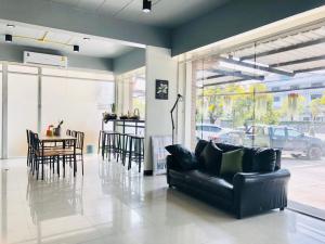 a living room with a black leather couch and a table at Best Bed Suvarnabhumi Hostel in Lat Krabang
