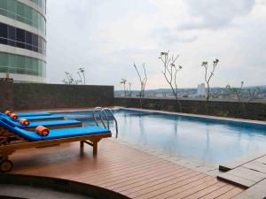 una piscina con tumbonas azules en un edificio en HARRIS Hotel Sentraland, en Semarang