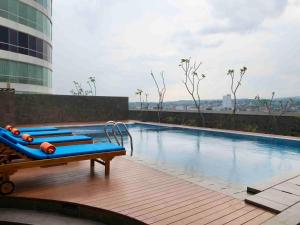a swimming pool with blue lounge chairs on a building at HARRIS Hotel Sentraland in Semarang