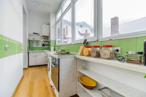 a kitchen with green and white walls and windows at Kronhaus in Braşov