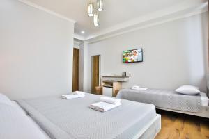 a white bedroom with two beds and a sink at Hotel Terrace Kutaisi in Kutaisi
