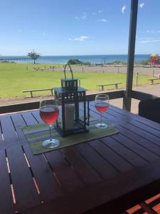 two glasses of red wine sitting on a wooden table at Pine View Holiday Rental in Emu Bay