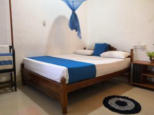 a bedroom with a bed with blue and white sheets at Alass Ga for pets lovers in Trincomalee