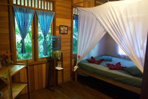 ein Schlafzimmer mit einem Bett und einem Fenster mit Vorhängen in der Unterkunft Nomad Divers Bangka in Manado