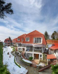 une grande maison avec un toit rouge dans l'établissement Marigold Sarovar Portico Shimla, à Shimla