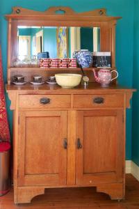 a wooden cabinet with a mirror and bowls on it at Fantail Cottage in Oamaru