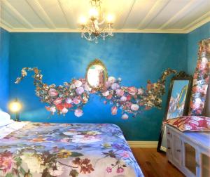 a bedroom with a blue wall with a bed and a mirror at Fantail Cottage in Oamaru