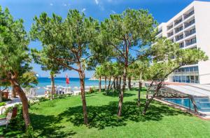 una vista della spiaggia dal balcone di un hotel con alberi di Tusan Beach Resort - All Inclusive a Kusadası