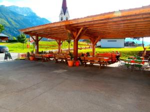 a wooden pavilion with tables and chairs in a field at Gasthof zum Löwen in Sankt Jakob im Lesachthale