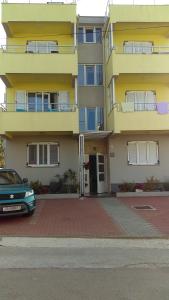un edificio amarillo con un coche aparcado delante de él en Apartments Diva, en Novalja
