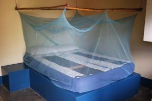 a bed with a net on top of it at Complexo Alemanha - Vilanculos Backpacker in Vilanculos