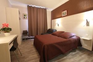 タラスコンにあるLe Provençalのベッドとデスクが備わるホテルルームです。