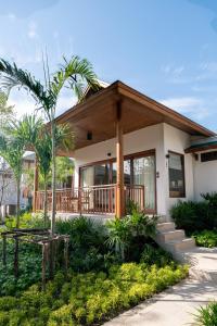 a house with a porch and a palm tree at Banana Fan Sea Resort in Chaweng