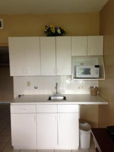 a kitchen with white cabinets and white appliances at Knights Inn Hallandale in Hollywood