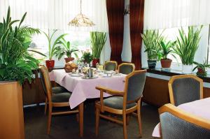 ein Esszimmer mit Tisch, Stühlen und Pflanzen in der Unterkunft Hotel Delfthalle in Emden