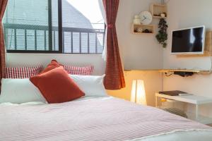 um quarto com uma cama com almofadas vermelhas e brancas em Cozy Vibes Apt Hotel em Tóquio