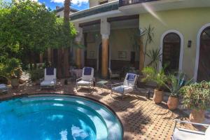 a swimming pool with chairs and a house at Palais El Arsat & Spa in Marrakesh