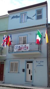 a blue building with flags on a balcony at La casa del pescatore in Oliveri