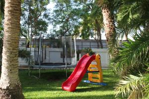 einen Spielplatz im Garten mit einer roten Rutsche in der Unterkunft Cuore Di Palme in Floridia