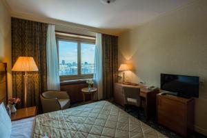 a hotel room with a bed and a desk and a television at President Hotel in Moscow