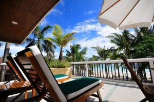 a balcony with chairs and an umbrella and palm trees at Henann Regency Resort and Spa in Boracay