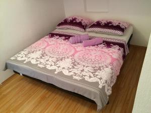een roze en wit bed met 2 kussens erop bij Apartmani Vesa in Primošten