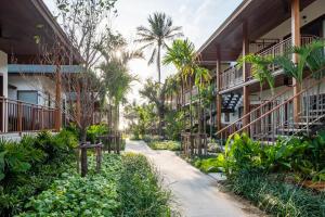 a walkway between two buildings with palm trees at Banana Fan Sea Resort in Chaweng